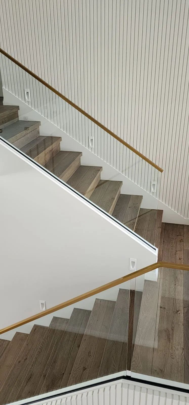 Staircase with wooden handrails and light-colored stone steps. Patterned wall on the side.