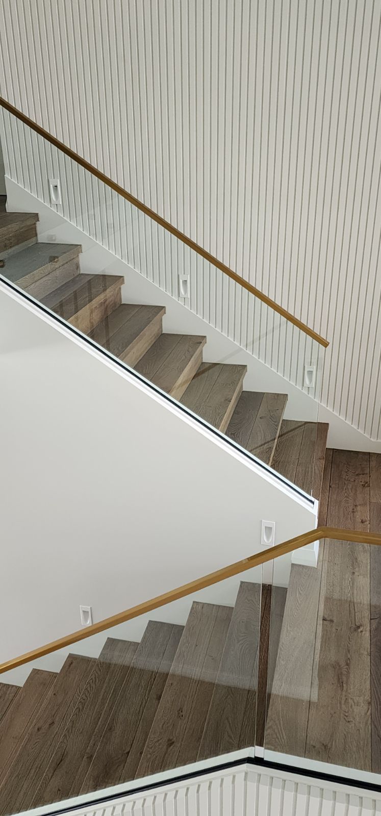 Staircase with wood steps and light brown wooden handrails. White walls with geometric pattern.