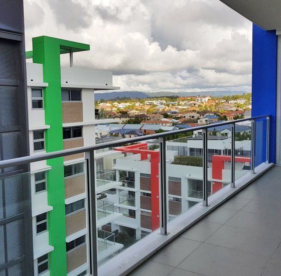 Balcony view of colorful apartment buildings and town, with mountains in the distance under cloudy skies.