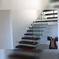 Modern wooden staircase with glass railing in a white room.