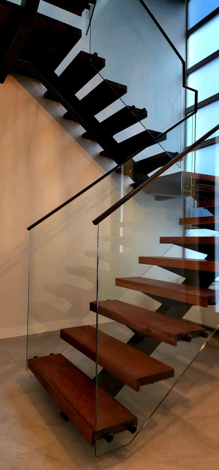 Modern wooden staircase with glass railing.