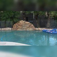 Swimming pool with rock feature and blue inflatable.