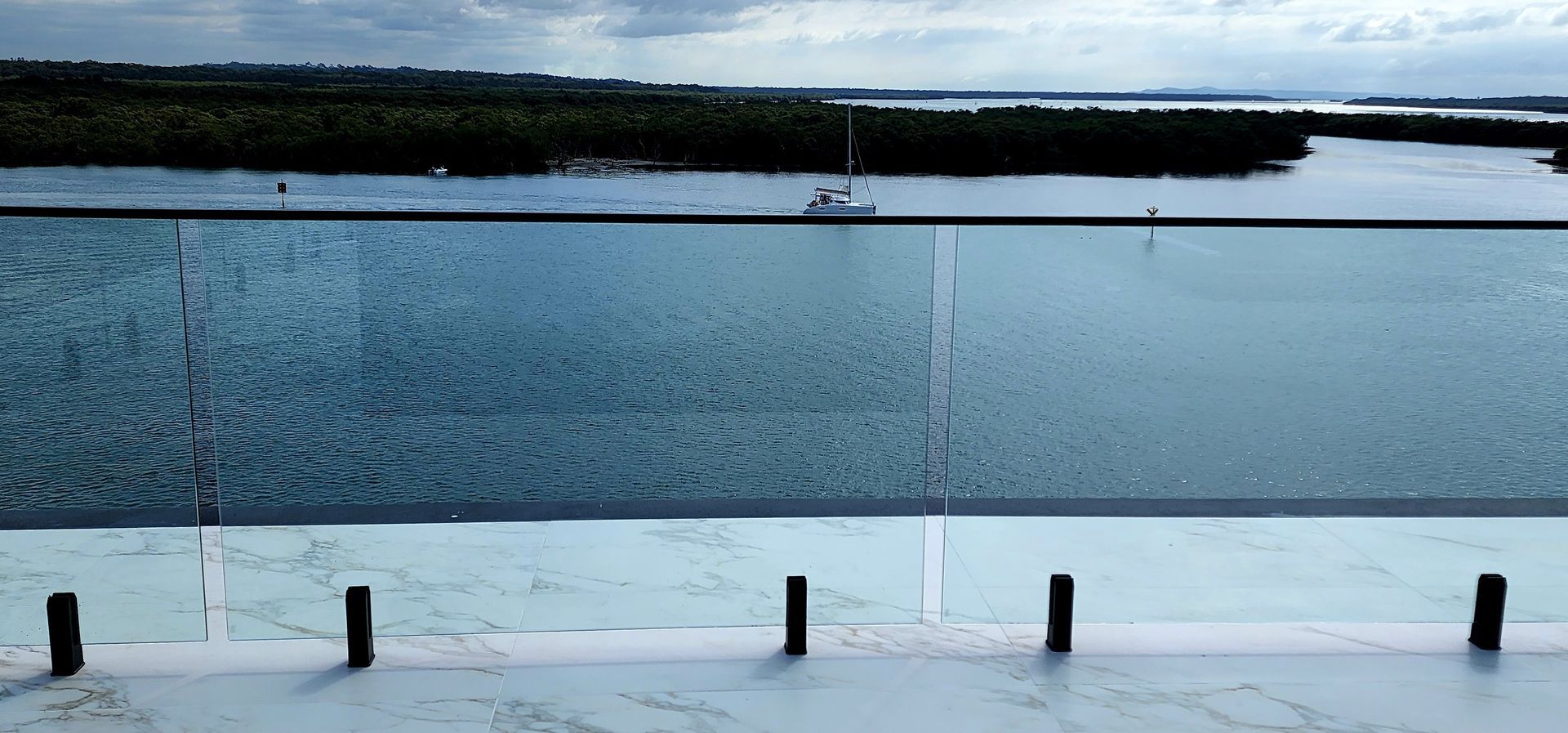Water pool with glassy walls overlooking water and trees.
