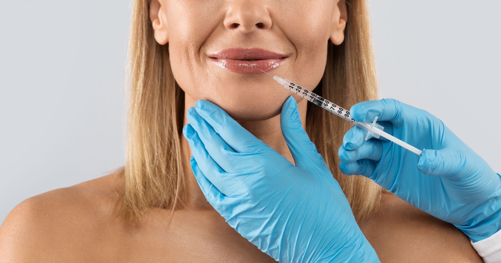 A woman is getting a botox injection in her lips.