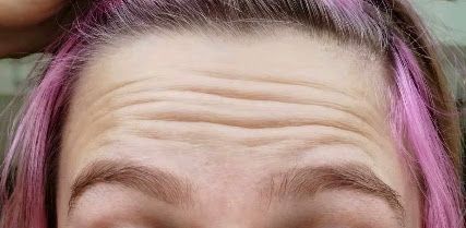 A close up of a woman 's forehead with pink hair.