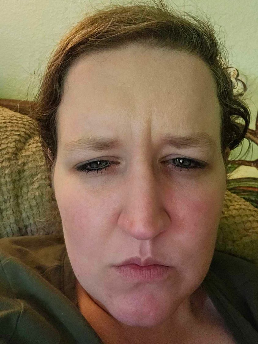 A woman is making a funny face while sitting on a couch.