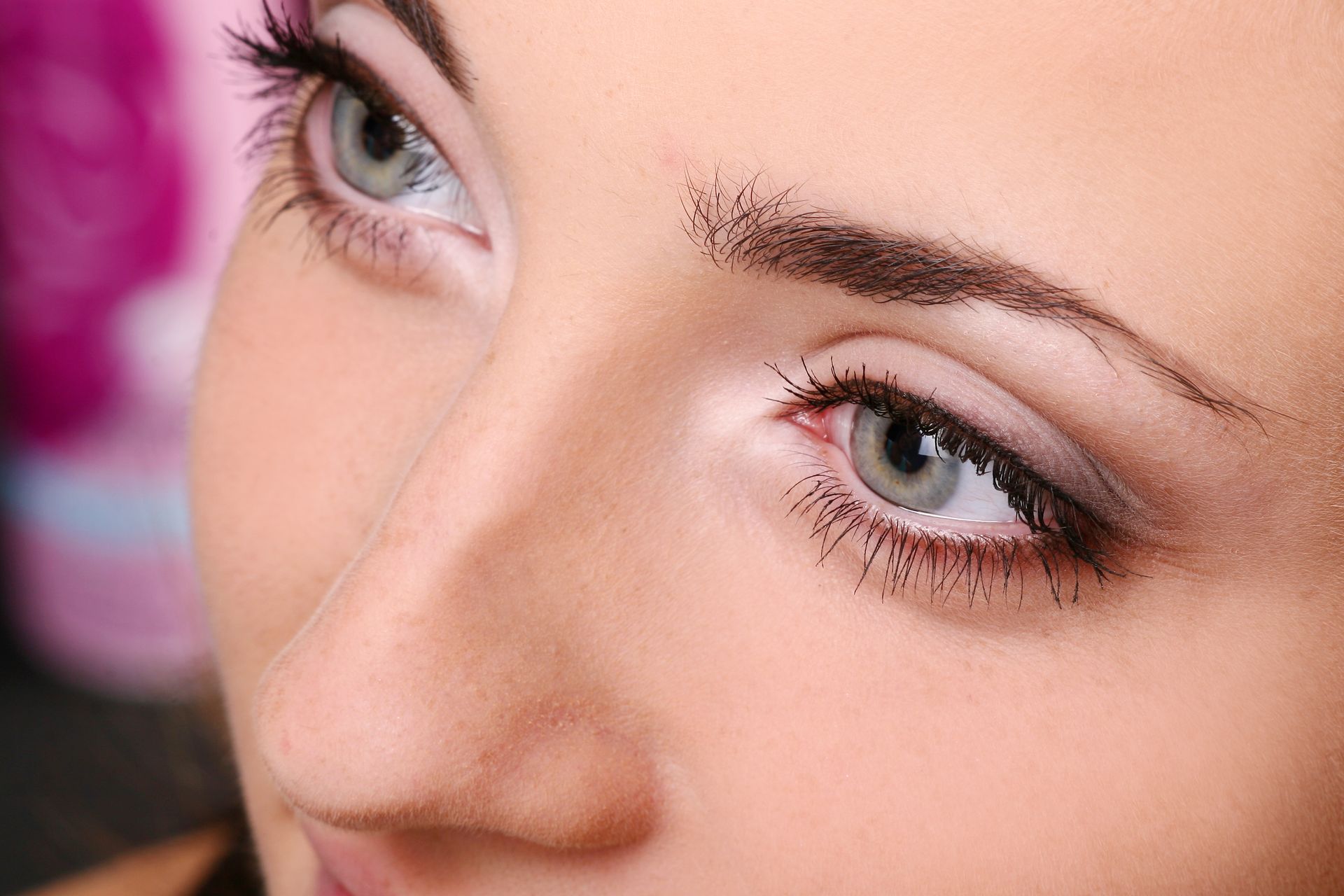 A close up of a woman 's face with blue eyes and long eyelashes.