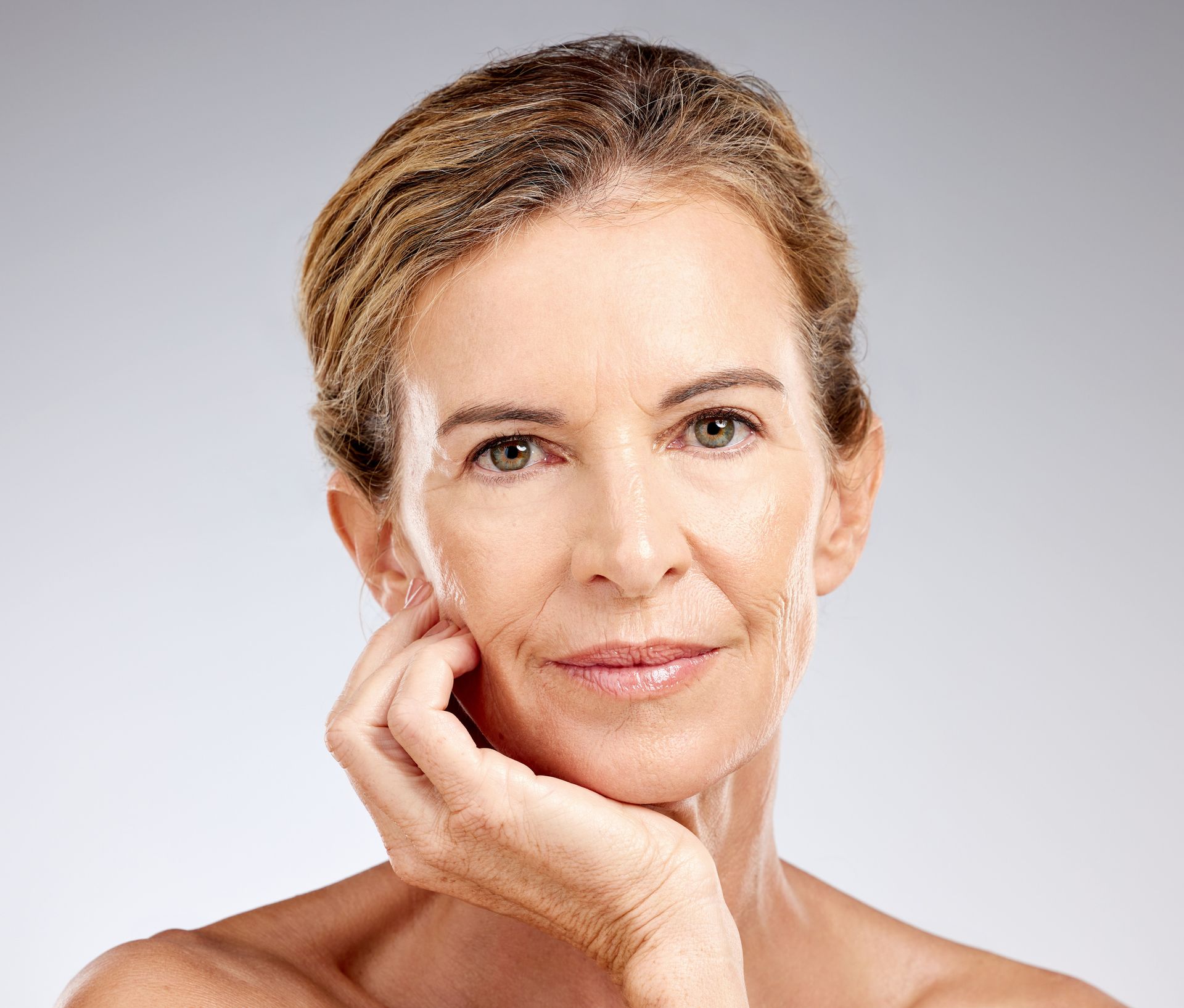 A close up of a woman 's face with her hand on her chin.