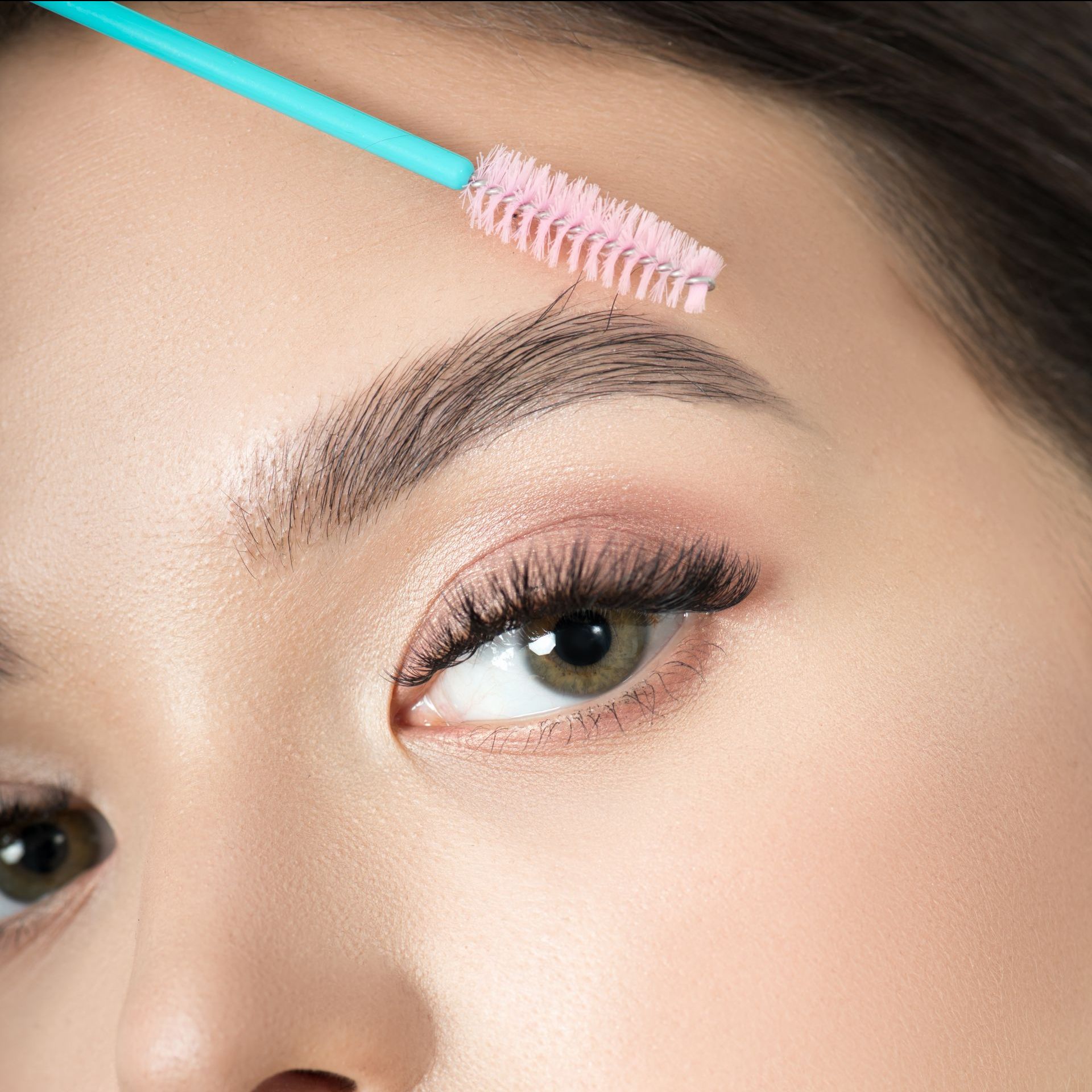 A woman is applying makeup to her eyebrows with a brush.