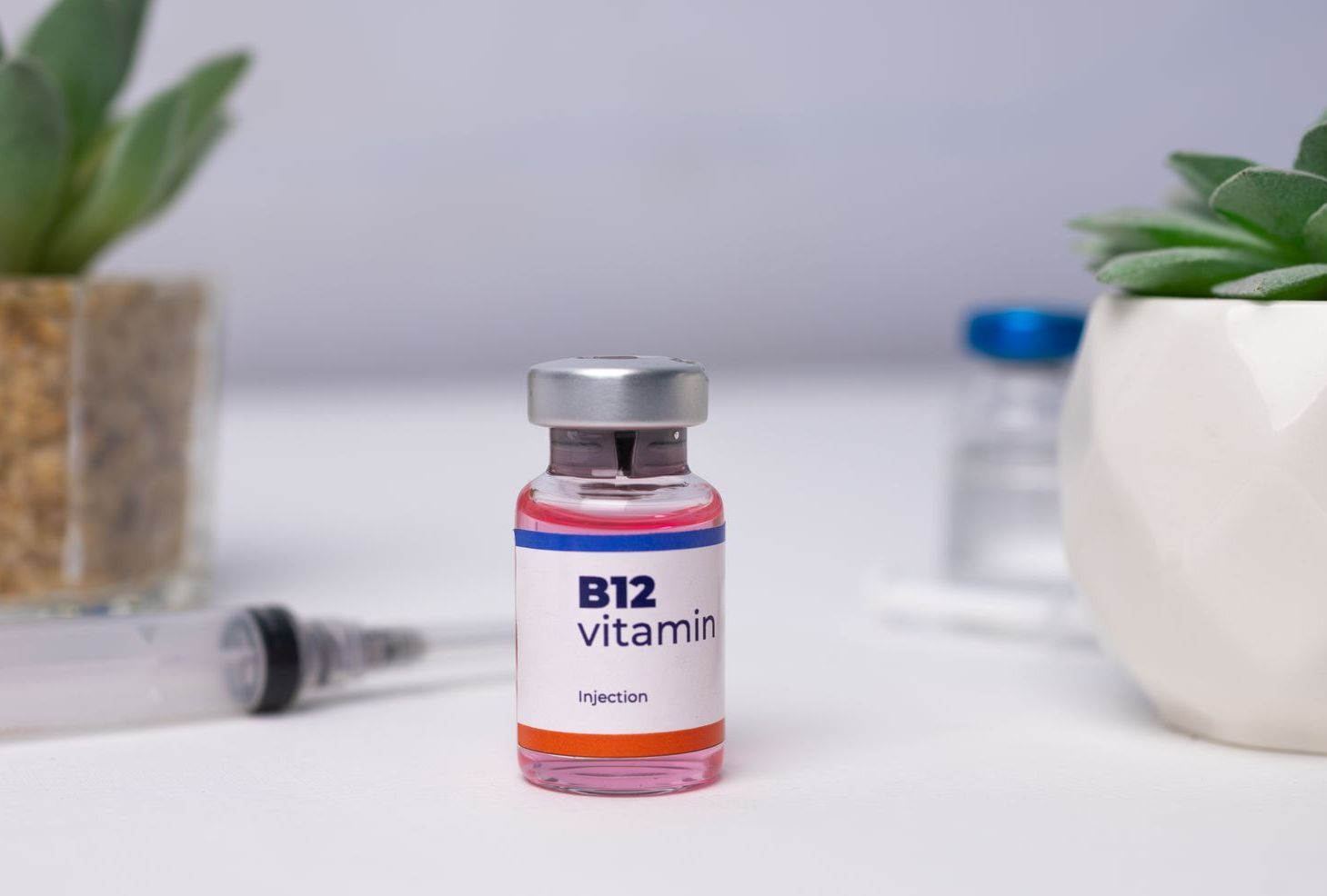 A bottle of b12 vitamins is sitting on a table next to a syringe.