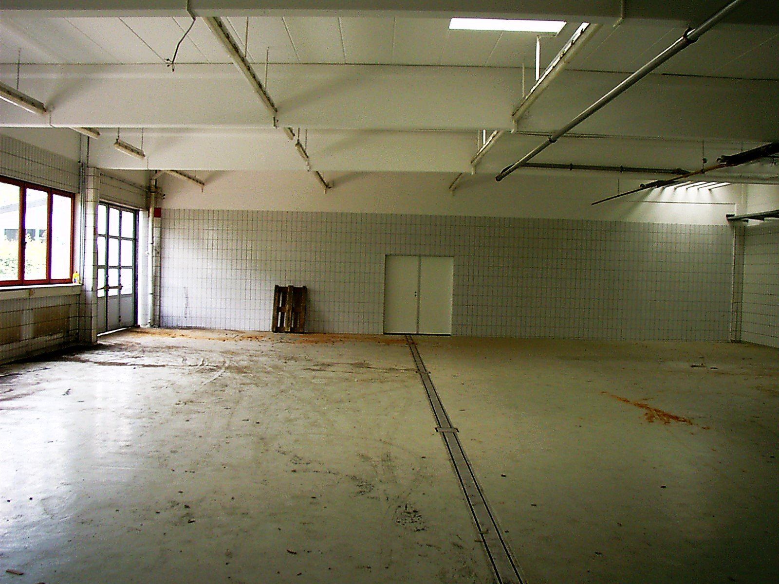 Ein großer leerer Raum mit gefliesten Wänden und einer Tür