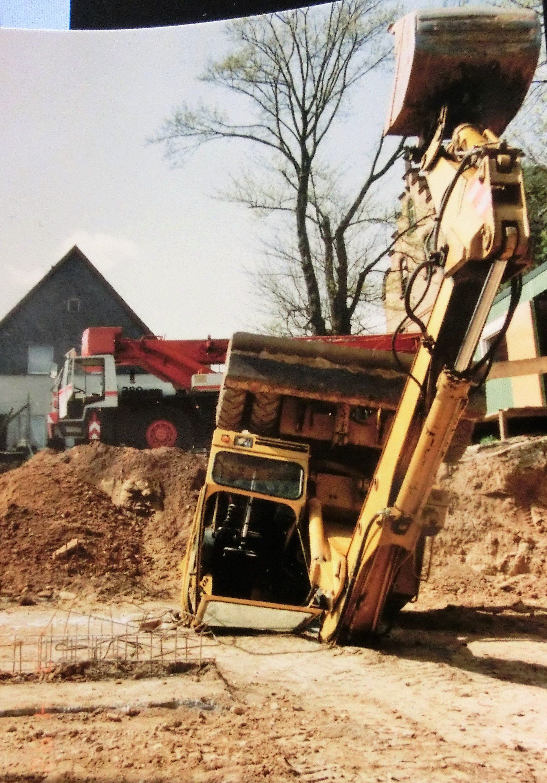 Ein gelber Bagger liegt auf der Seite auf einem Feld