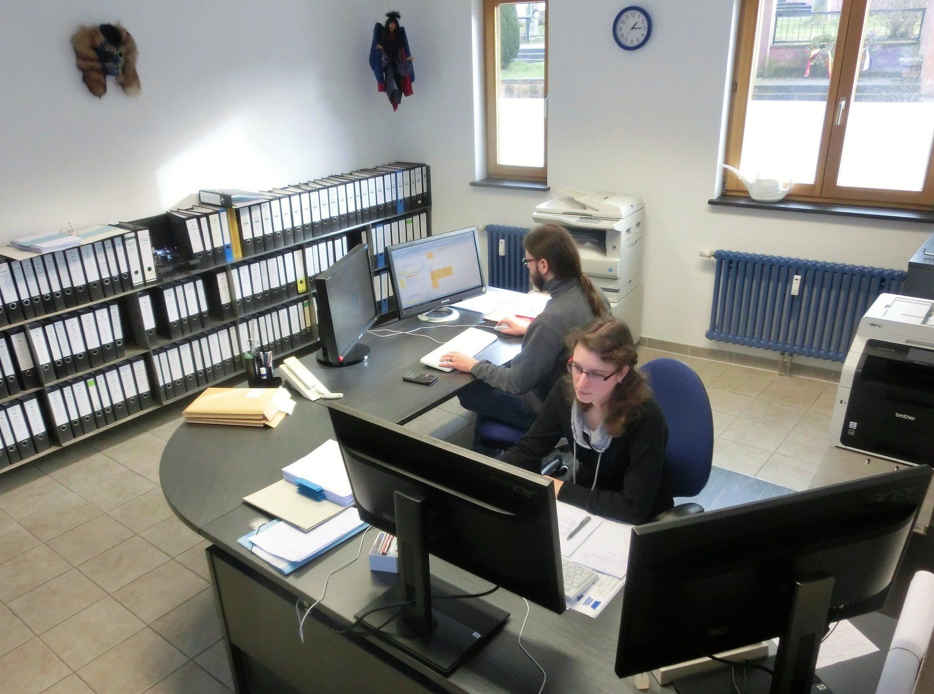 Ein Mann und eine Frau sitzen an einem Schreibtisch mit Computern