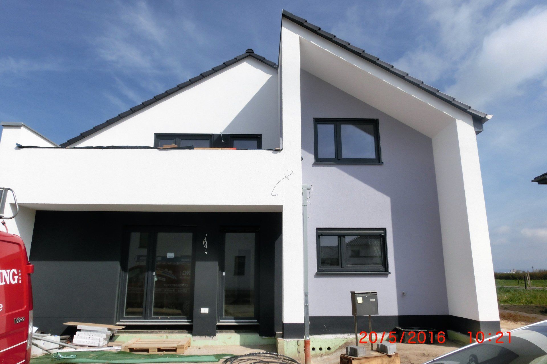 Ein weiß-schwarzes Haus mit einem davor geparkten roten Lieferwagen