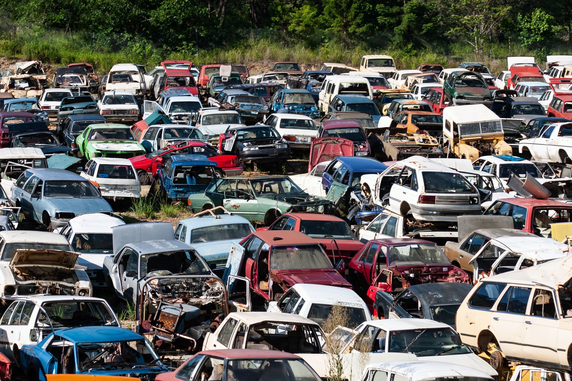 Crowded junkyard with rows of old, damaged cars for auto salvage and recycling.