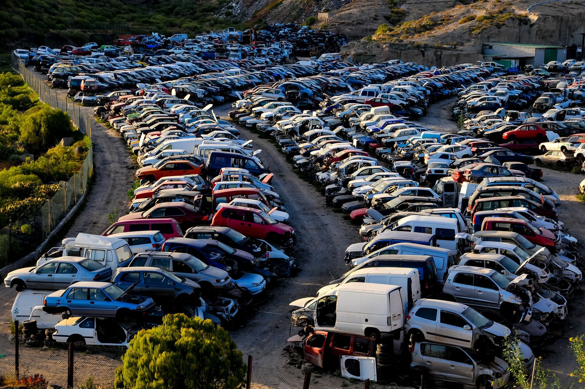 Large junkyard with rows of scrapped cars and vehicles for auto parts recycling.