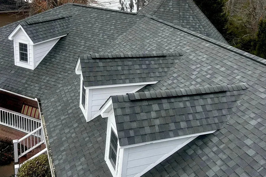 Worker on a red-tiled roof with scaffolding, repairing the roof near a skylight.