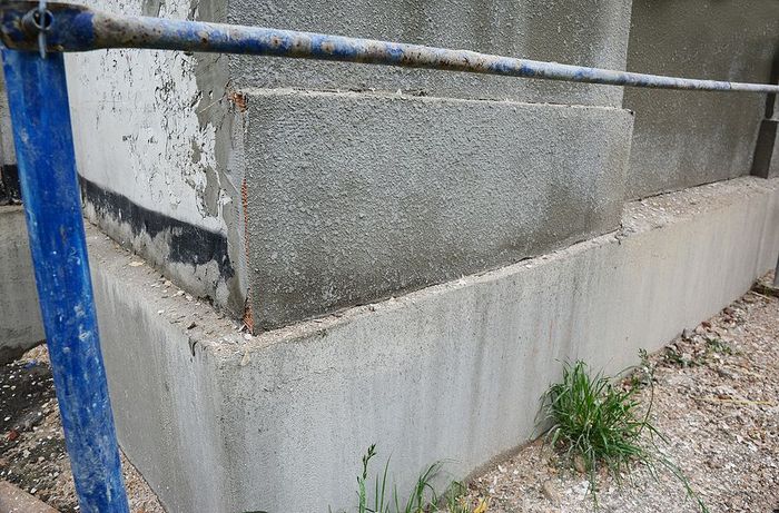 a cement wall with a blue metal fence