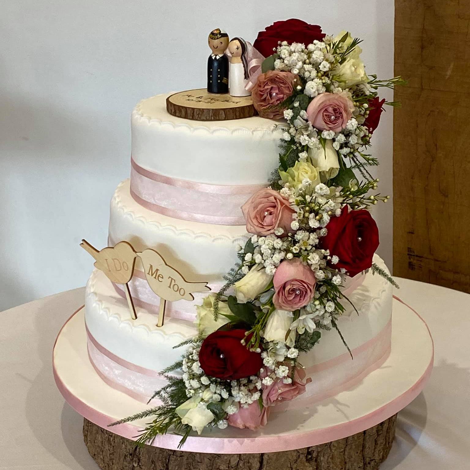 a wedding cake with flowers and a bride and groom figurine on top .