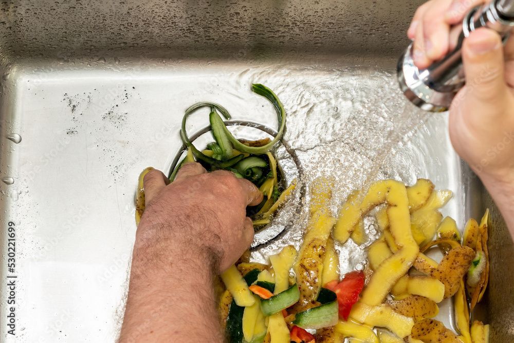 A person is washing vegetables in a sink.
