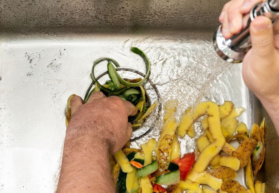 A person is washing vegetables in a sink.