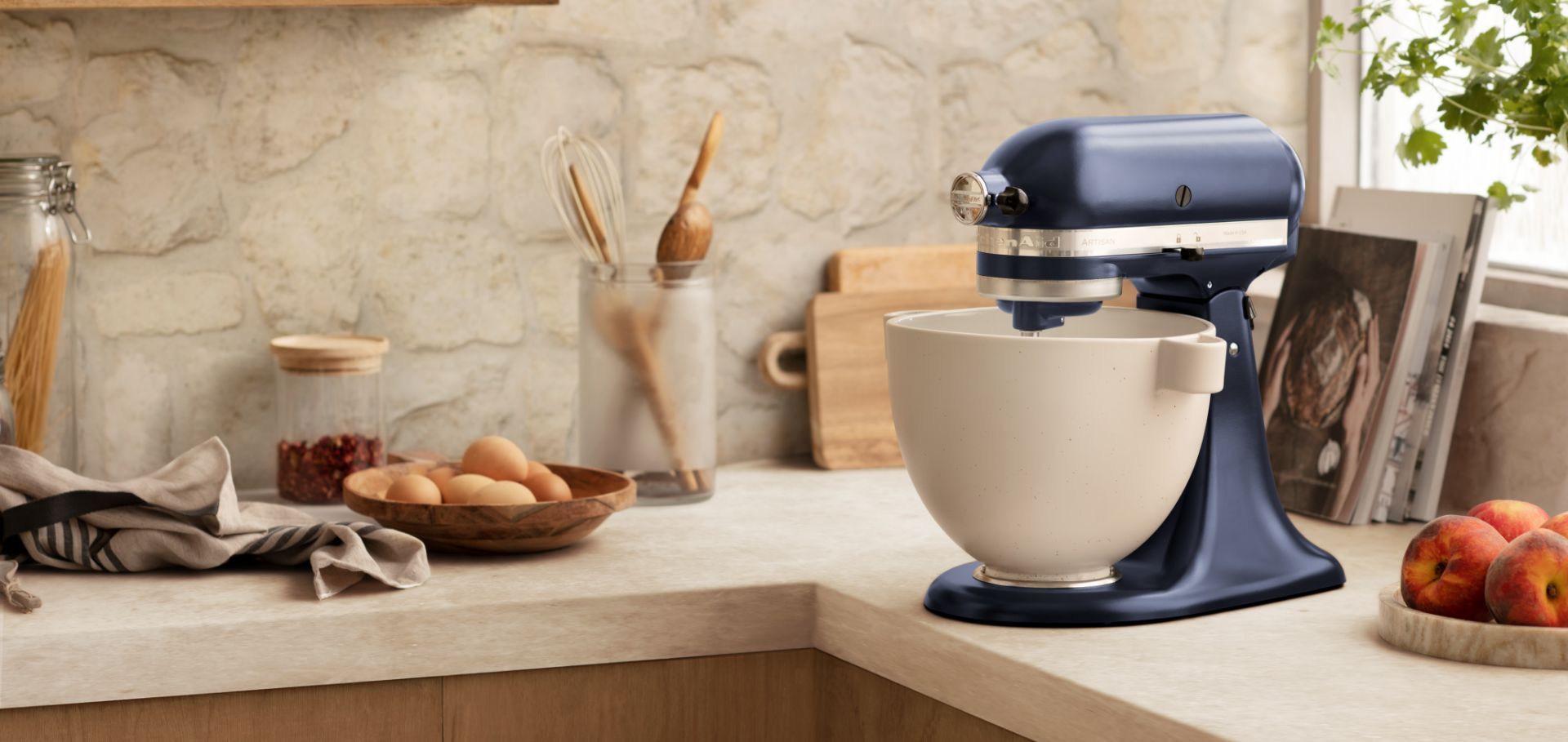 A kitchenaid mixer is sitting on a counter next to a bowl of eggs.