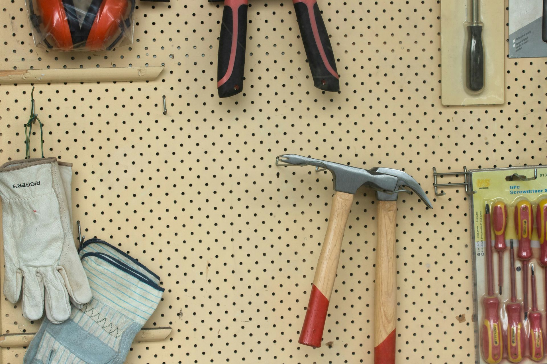 A bunch of tools are hanging on a peg board