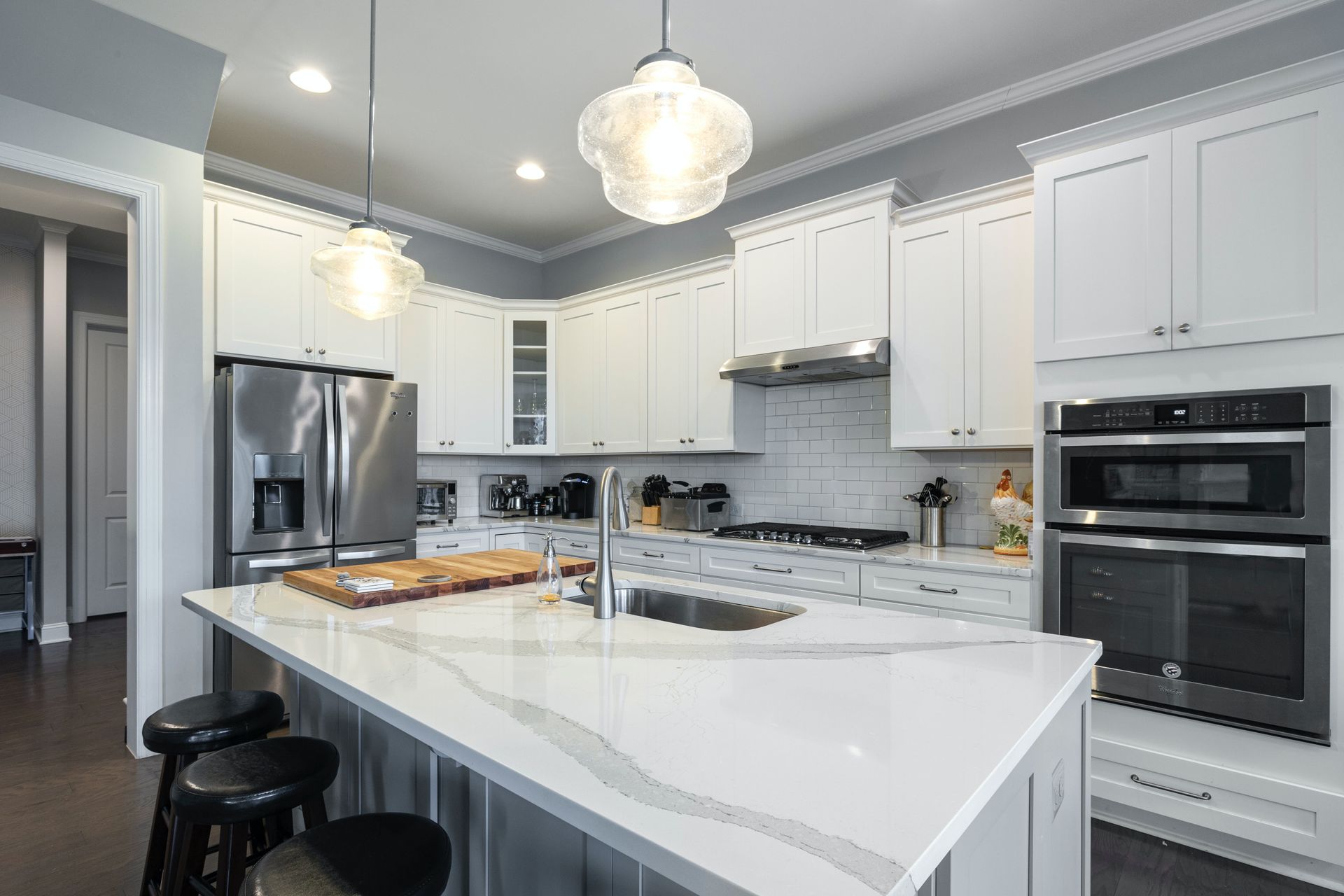 A kitchen with white cabinets , stainless steel appliances , a sink , and a large island.