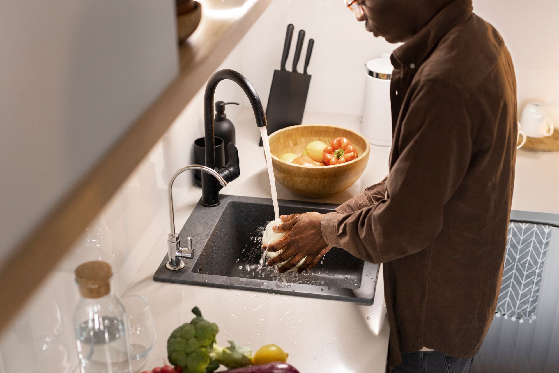 A man is washing his hands in a kitchen sink.