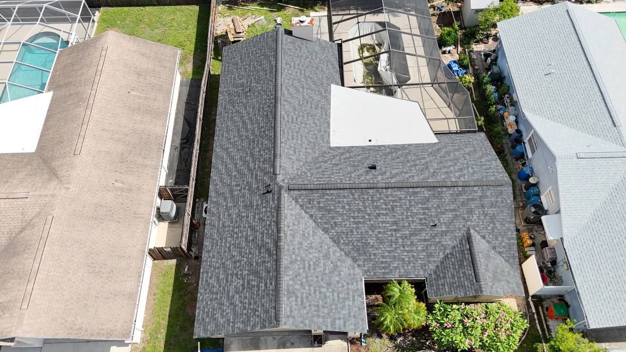 An aerial view of a house with a grey shingle roof and a window.