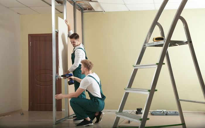 two repairman drilling the wall