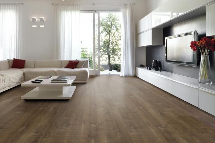 Soggiorno moderno con mobili bianchi, pavimenti in legno scuro e una grande finestra che si affaccia su uno spazio verde.