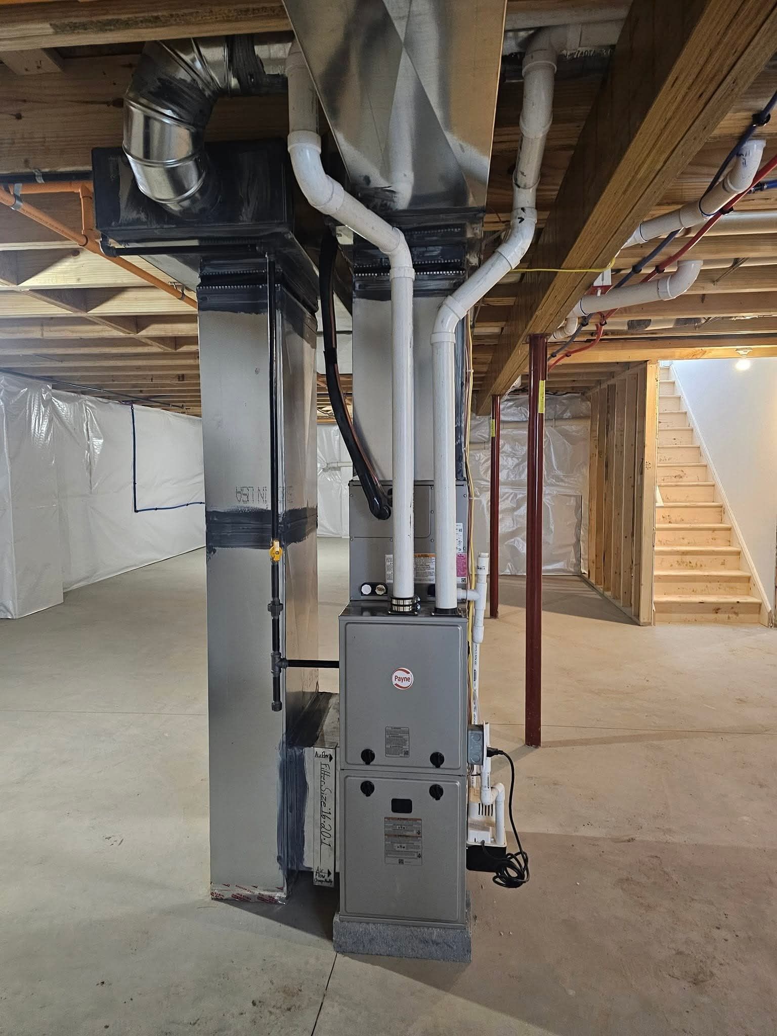 Industrial chillers and ventilation equipment outside a building on a gravel base.
