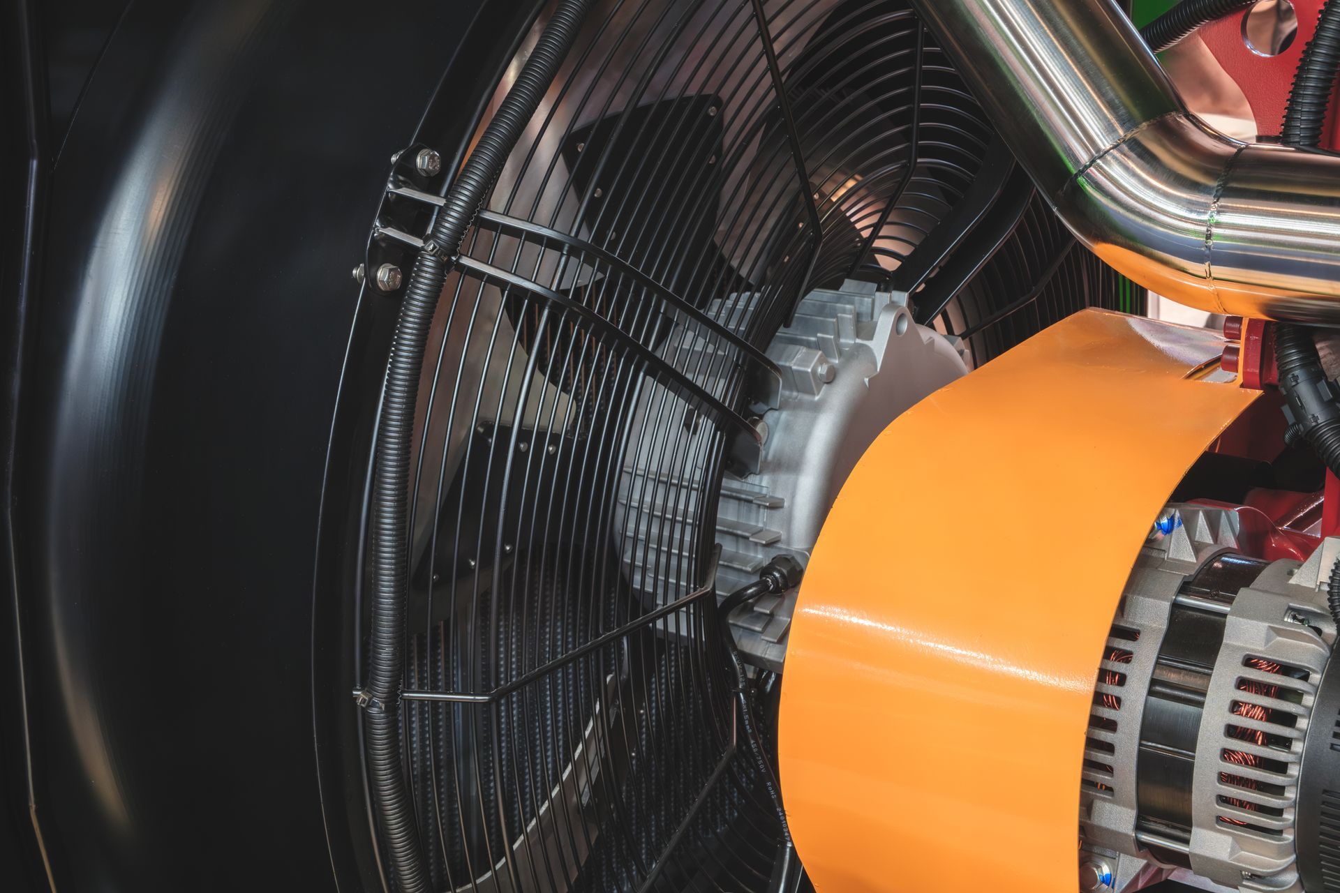 Large black industrial fan with orange shroud and silver metal components.