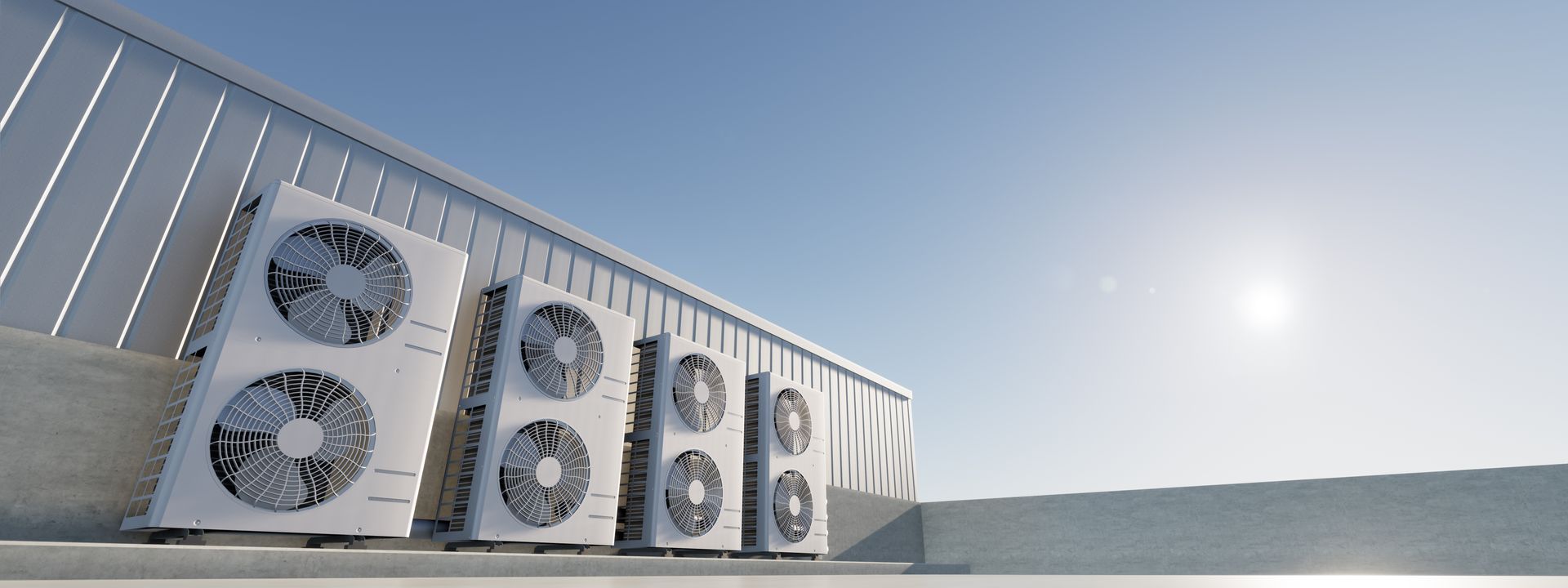 Air conditioning units on a rooftop against a clear blue sky with the sun shining.