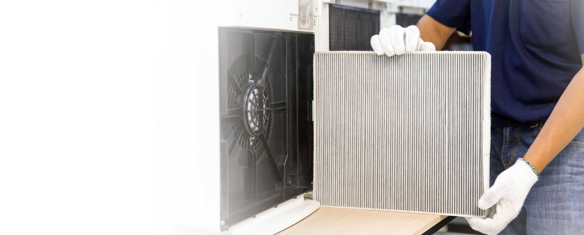 Person wearing gloves removes or installs an air filter from an HVAC unit.