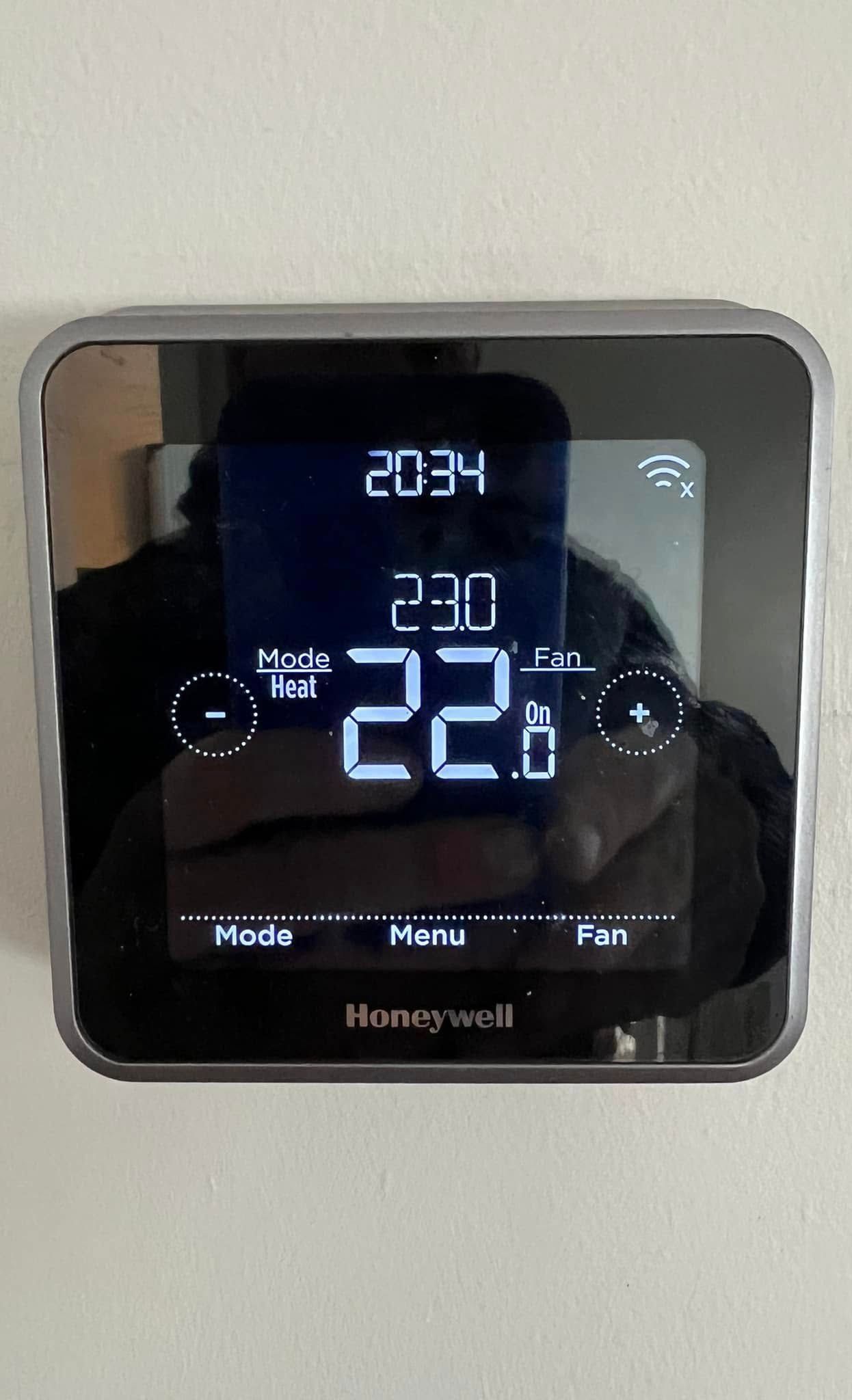 Un thermostat Honeywell est posé sur un mur blanc.