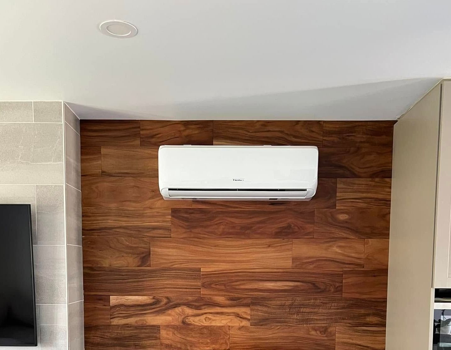 Un climatiseur noir est posé sur le côté d'une maison à côté d'une fenêtre.