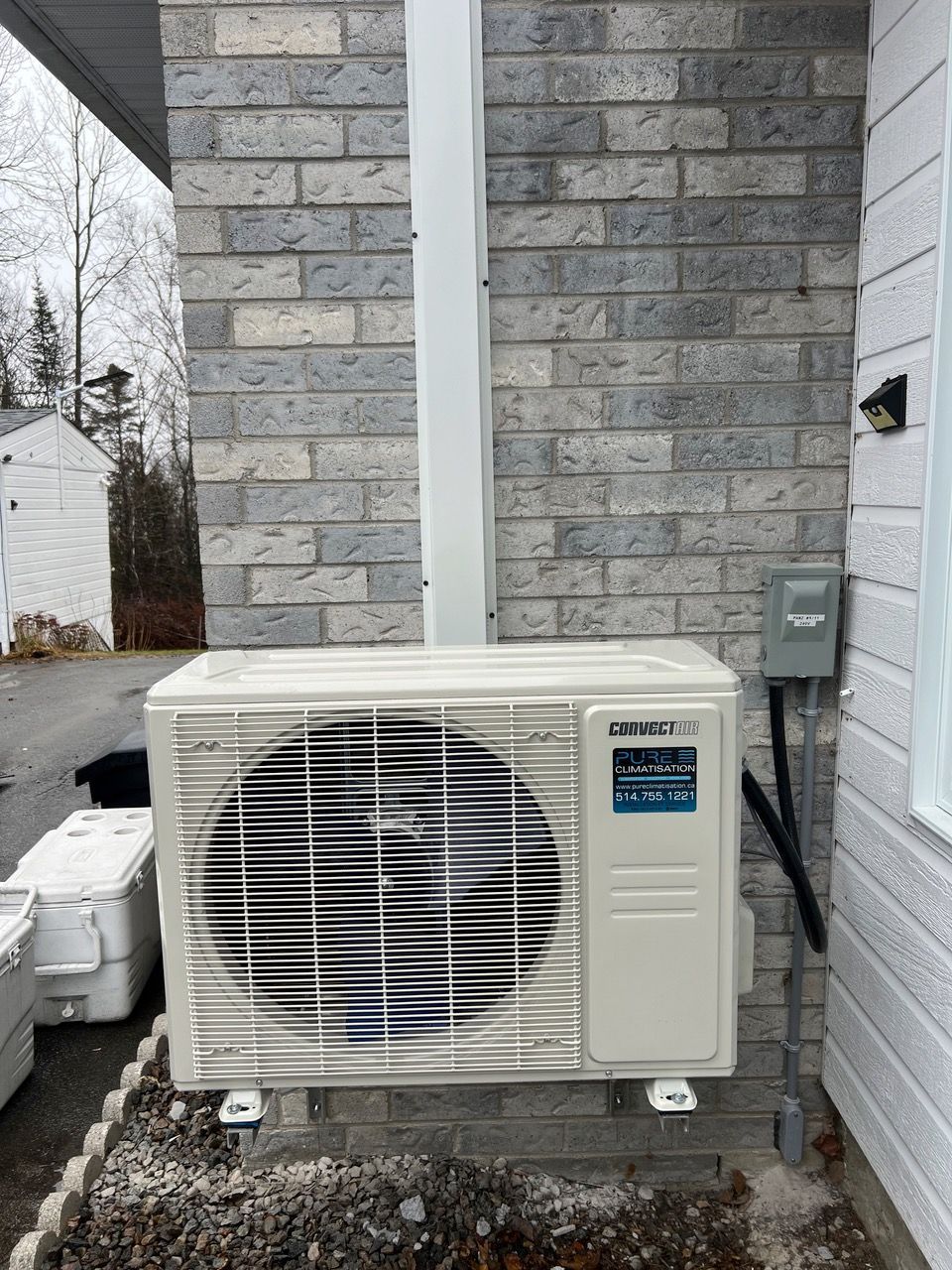 Un climatiseur blanc est monté sur le côté d'un bâtiment en briques.