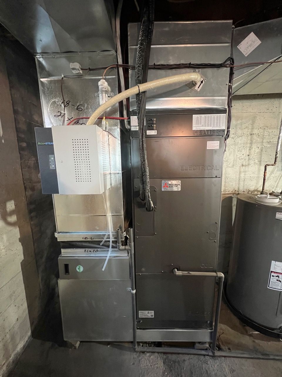 Un système de chauffage et de refroidissement est installé dans un sous-sol à côté d'un chauffe-eau.