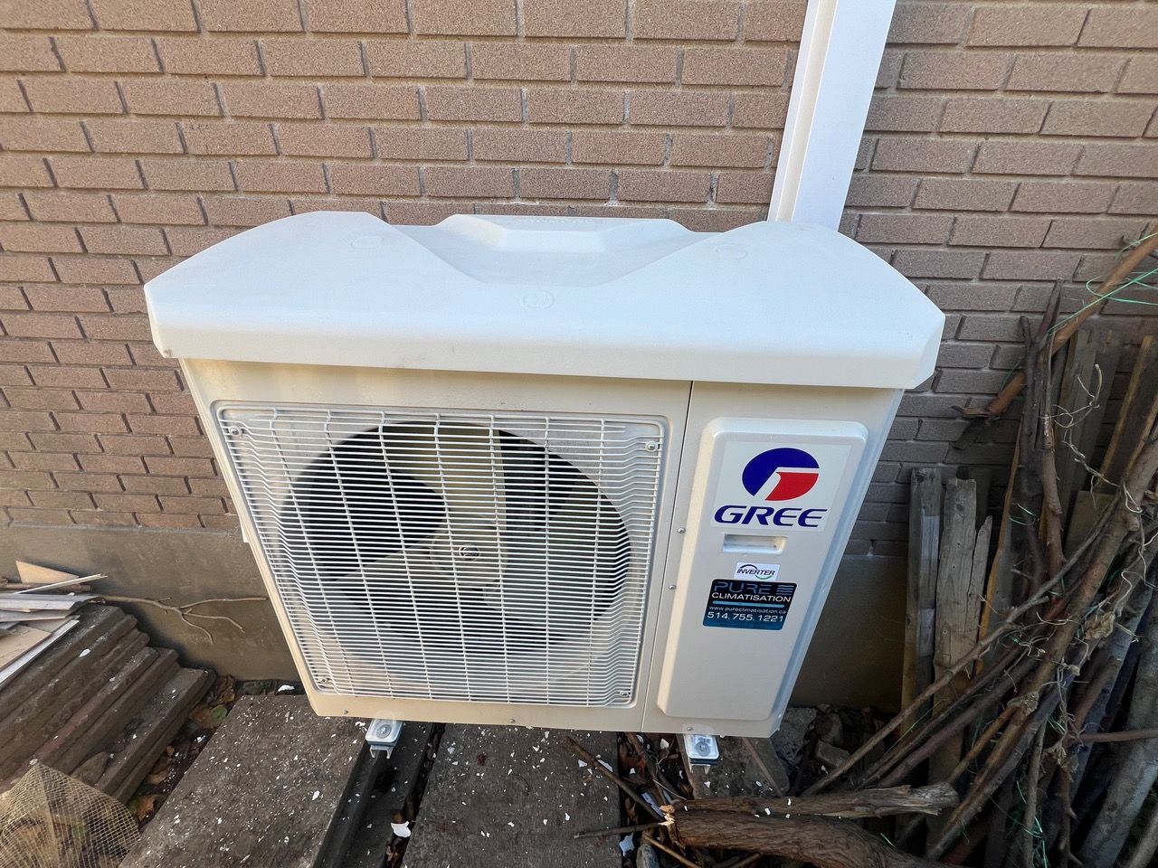 Un climatiseur gree est monté sur le côté d'un bâtiment en briques.