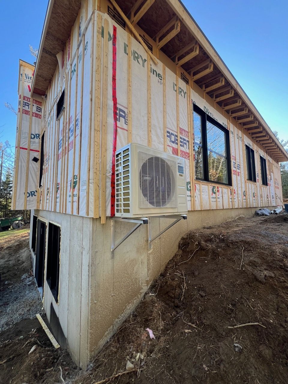 Une maison est en construction avec un grand climatiseur sur le côté.