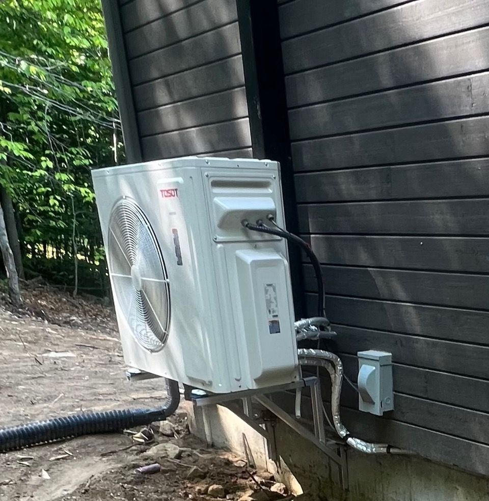Un climatiseur blanc est fixé sur le côté d'une maison.