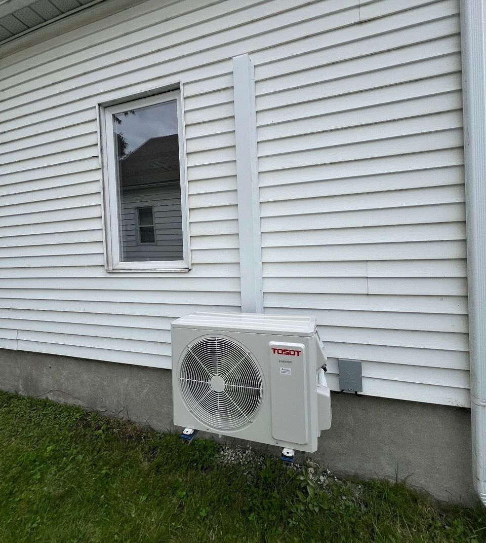 Une maison blanche avec une fenêtre et un ventilateur sur le côté.