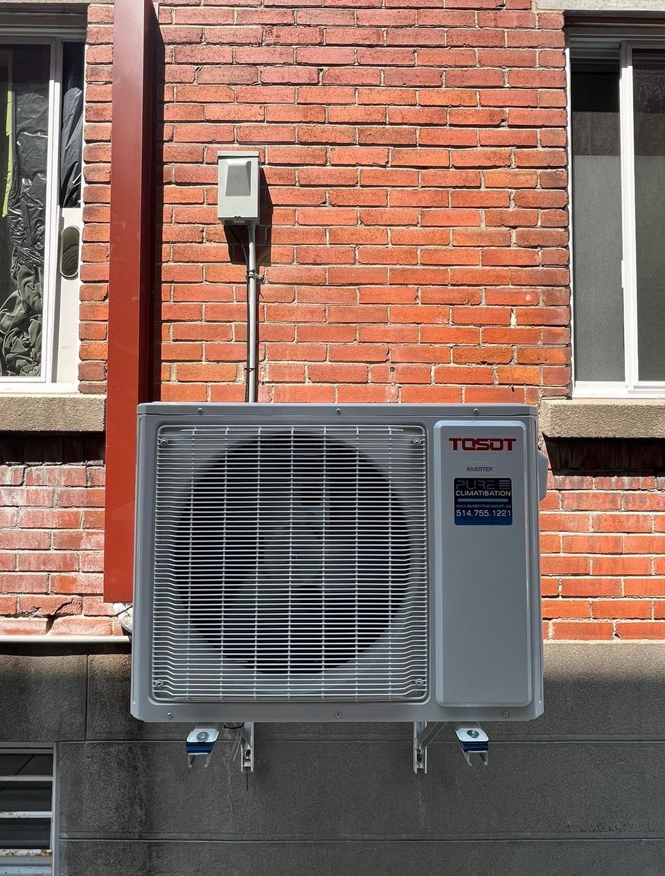 Un climatiseur tocdet est monté sur le côté d'un bâtiment en briques