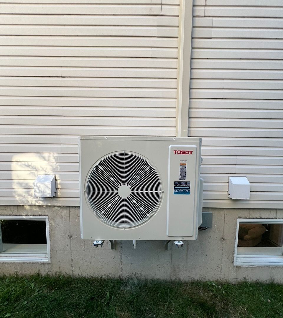 Un climatiseur blanc est monté sur le côté d'une maison.