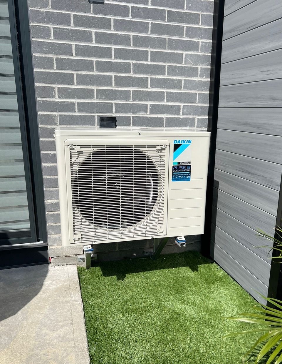 Un climatiseur blanc est posé sur le côté d'un bâtiment en briques.