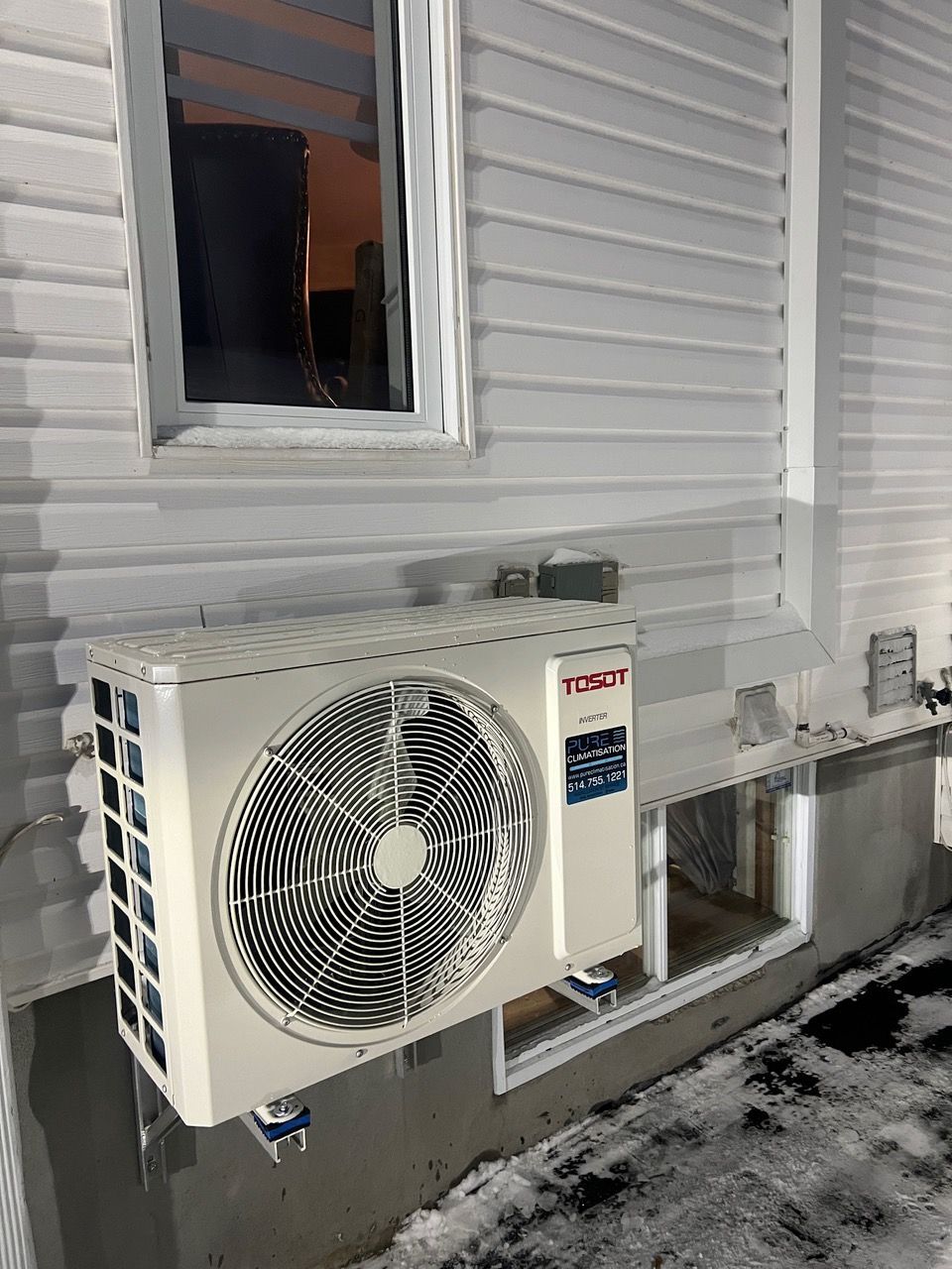 Un climatiseur blanc est monté sur le côté d'une maison.