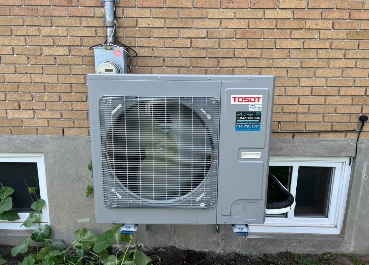 Un climatiseur tosot est monté sur le côté d'un bâtiment en briques.