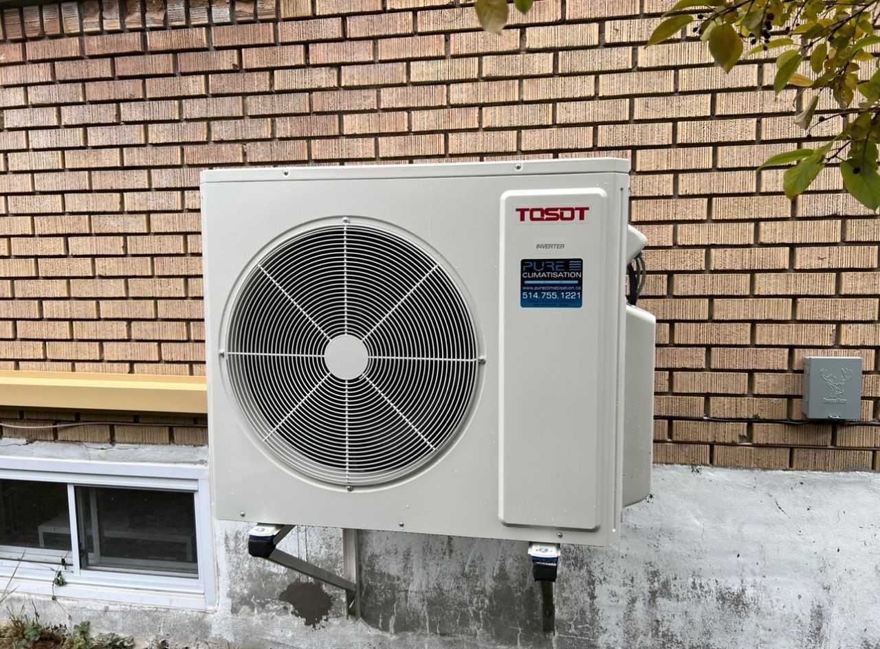 Un climatiseur tosot est monté sur le côté d'un bâtiment en briques.